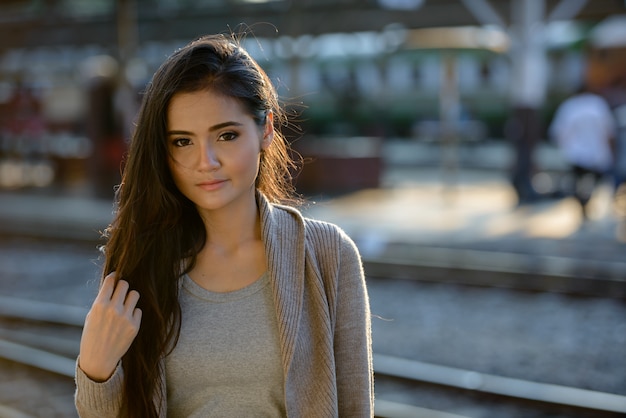 Retrato de joven bella mujer asiática en la estación de tren