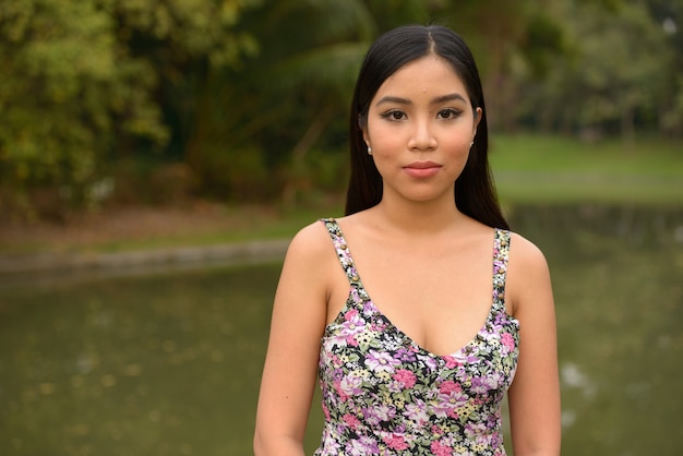 Retrato de joven bella mujer asiática relajante en el parque al aire libre