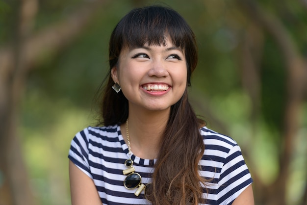 Retrato de joven bella mujer asiática relajante en el parque al aire libre