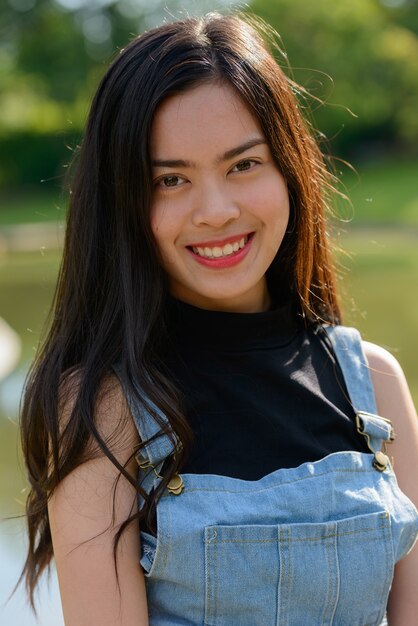 Retrato de joven bella mujer asiática relajante en el parque al aire libre