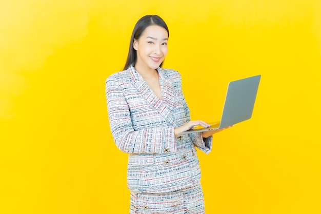 Retrato joven y bella mujer asiática sonríe con ordenador portátil en la pared aislada
