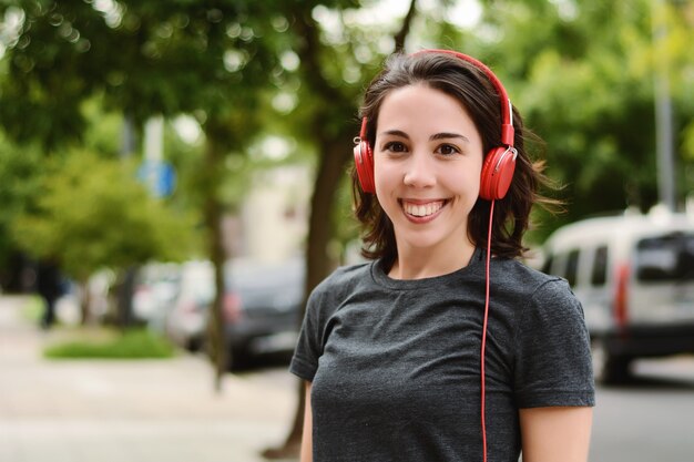 Retrato de joven bella mujer con auriculares rojos escuchando música