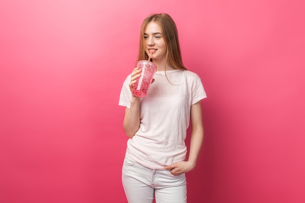 Retrato de joven y bella mujer bebiendo bebidas gaseosas de una botella con una pajita