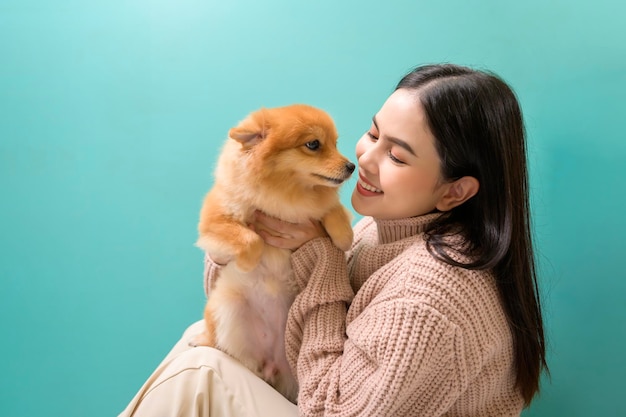 Retrato de joven bella mujer besa y abraza a su perro sobre fondo verde