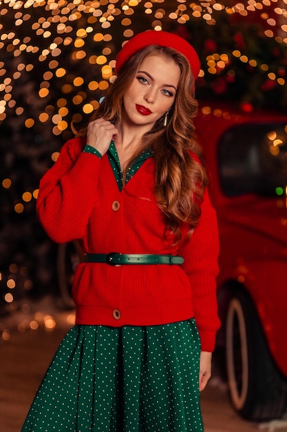 Retrato de una joven y bella mujer con una boina roja con el telón de fondo de las luces de Navidad