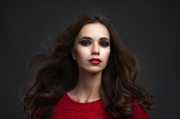 Retrato de la joven y bella mujer con cabello largo y castaño posando en el estudio