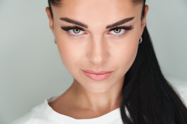 Retrato de joven bella mujer con cabello oscuro y pestañas largas