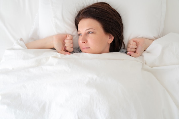 Retrato de joven bella mujer en la cama estirando después de despertarse