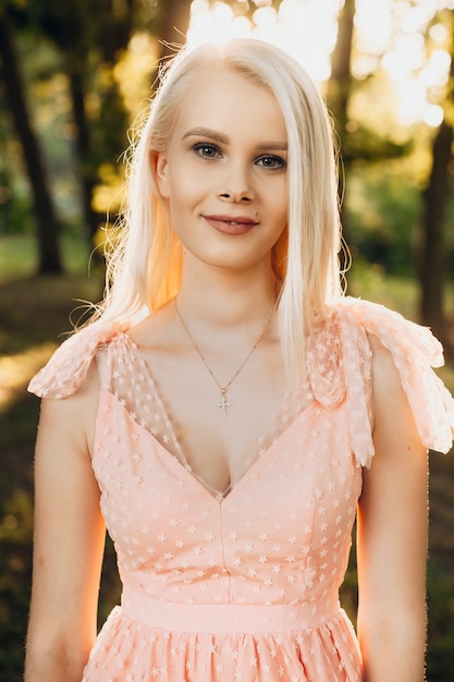 Retrato de joven bella mujer caucásica mirando a la cámara sonriendo. Linda joven rubia posando al aire libre.