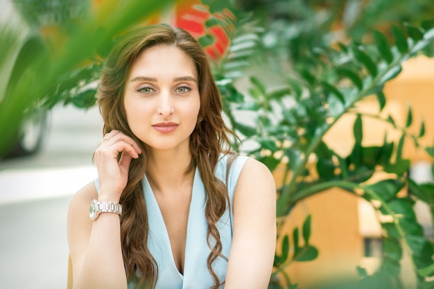 Retrato de una joven y bella mujer caucásica sentada en el jardín de flores al aire libre