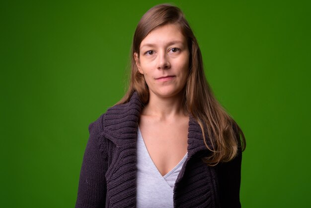 Retrato de joven bella mujer contra la pared verde