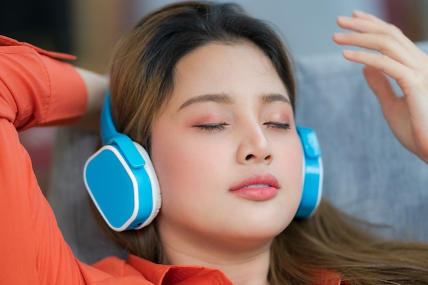 Retrato de joven bella mujer disfrutando de la música con rostro sonriente sentado junto a la ventana en la oficina creativa o cafetería