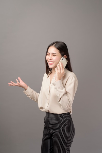 Retrato de joven bella mujer está utilizando el teléfono celular en gris