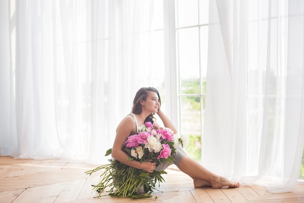 Retrato de joven bella mujer con flores en el interior de cerca