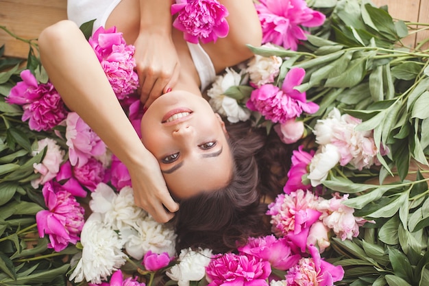 Retrato de joven bella mujer con flores en el interior de cerca