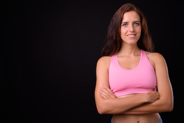 Retrato de joven bella mujer lista para el gimnasio contra la pared negra