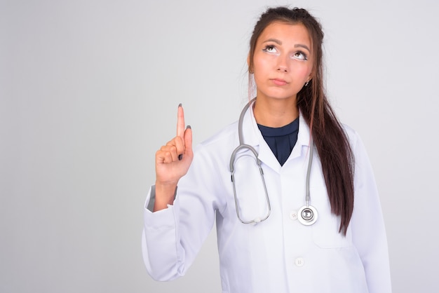 Retrato de joven bella mujer médico contra la pared blanca