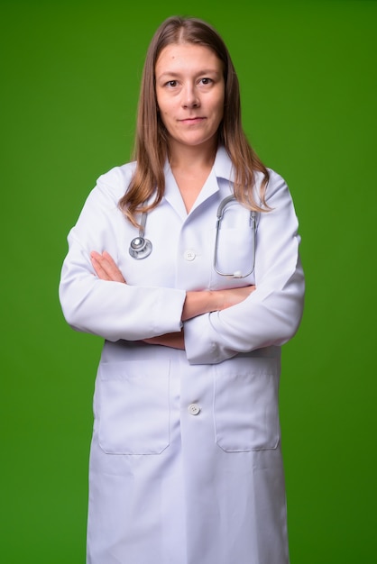 Retrato de joven bella mujer médico contra la pared verde