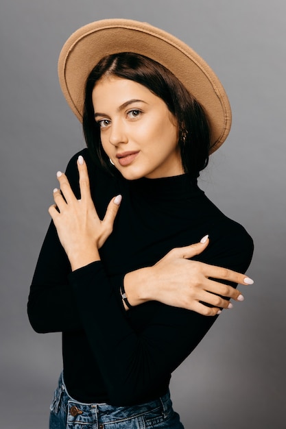 Retrato de una joven y bella mujer de moda en traje negro y sombrero. Foto de alta calidad