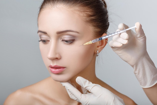 Foto retrato de joven bella mujer recibiendo inyección de elevación cosmética en la cara. operacion plastica. tratamiento cosmético