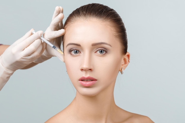 Retrato de joven bella mujer recibiendo inyección de elevación cosmética en la cara. Operacion plastica. Tratamiento cosmético