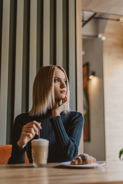 Retrato de una joven y bella mujer rubia con café