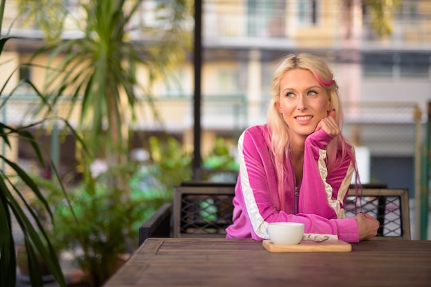 Retrato de joven bella mujer rubia relajante en la cafetería.