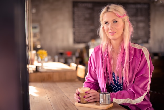 Retrato de joven bella mujer rubia relajante en la cafetería.