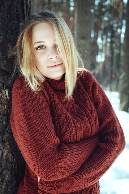 Retrato de una joven y bella mujer rubia en suéter posando en Winter Park. Día soleado en Forrest.