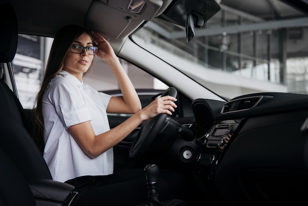 Retrato de joven bella mujer sentada en el coche