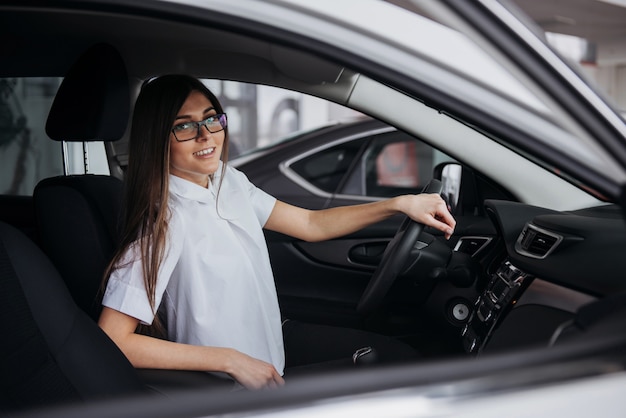 Retrato de joven bella mujer sentada en el coche