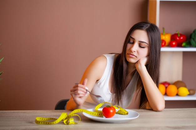 Retrato de joven bella mujer con tomate y cinta métrica en placa