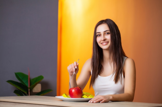 Retrato de joven bella mujer con tomate y cinta métrica en placa