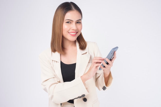 Retrato de joven bella mujer en traje con teléfono inteligente sobre fondo blanco.