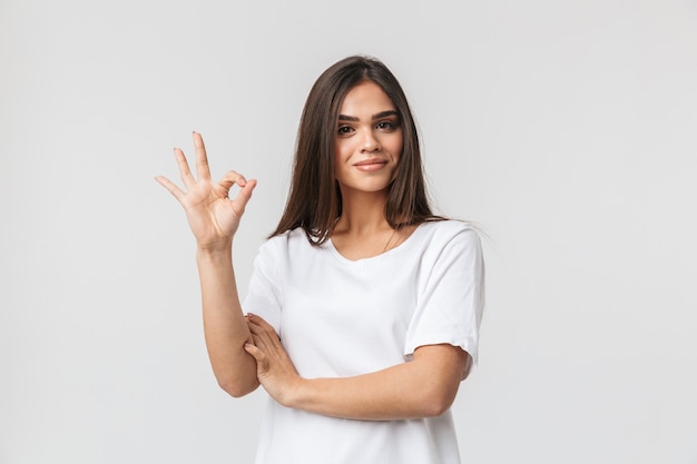 Retrato de una joven y bella mujer vestida casualy de pie aislado en blanco, ok