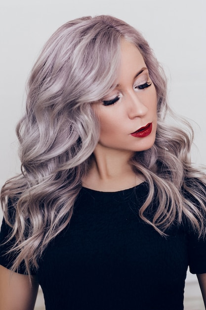 Foto retrato de joven bella mujer en vestido negro con cabello rubio gris y maquillaje