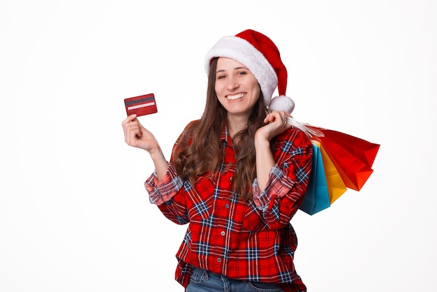 Retrato joven y bella mujer vistiendo gorro de Papá Noel de Navidad con bolsas de compras y tarjeta de crédito