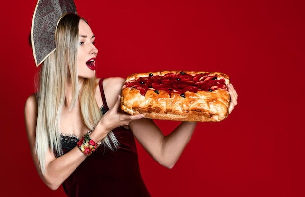 Retrato de una joven y bella rubia sosteniendo un delicioso pastel de cereza casero