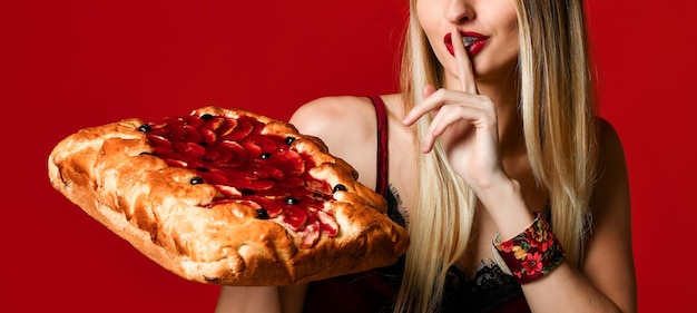 Retrato de una joven y bella rubia sosteniendo un delicioso pastel de cereza casero