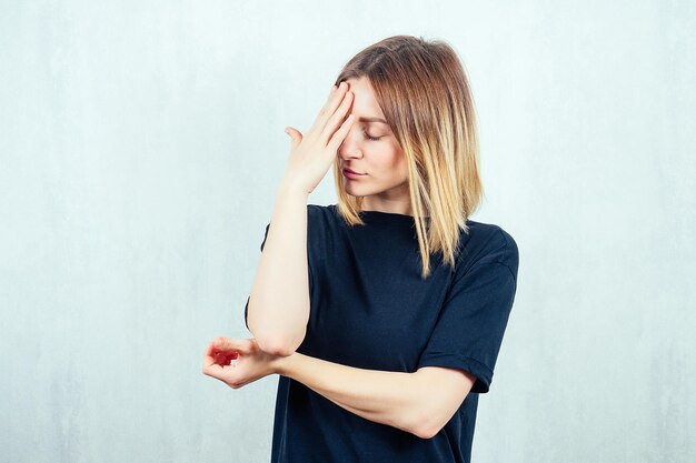 Retrato de una joven y bella rubia sosteniendo su mano en la cabeza con una camiseta negra. concepto del ciclo menstrual y cabeza de dolor de migraña.