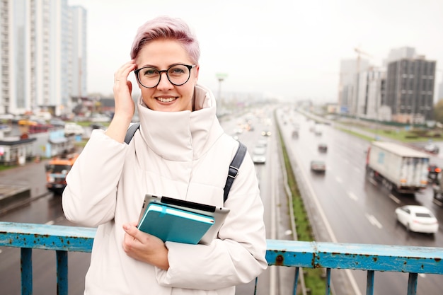 Retrato de joven blogger feliz con portátil moderno y cuadernos al aire libre