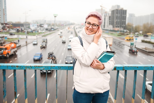 Retrato de joven blogger feliz con portátil moderno y cuadernos al aire libre