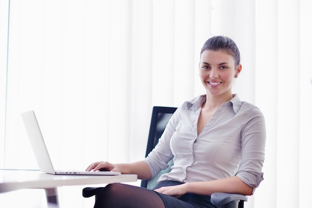 retrato de una joven y bonita mujer de negocios que trabaja en una computadora portátil en la oficina moderna y luminosa en el interior
