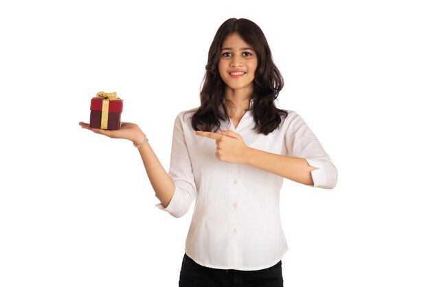 Retrato de una joven bonita sosteniendo y posando con una caja de regalo en un fondo blanco