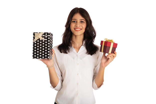 Retrato de una joven bonita sosteniendo y posando con una caja de regalo en un fondo blanco