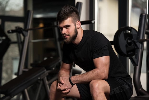 Retrato de un joven en buena forma física descansando en un club moderno de salud