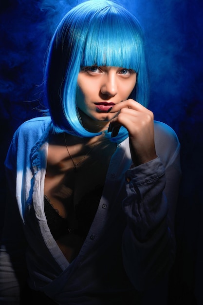 Retrato de una joven con cabello azul sobre un fondo negro con humo azul