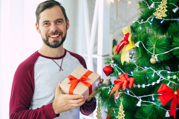 Retrato joven con caja de regalo en casa en Navidad