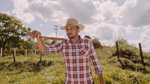 retrato, de, joven, en, el, camisa casual, tenencia, el suyo, azada, en, el, granja, herramienta agrícola, hombre latino