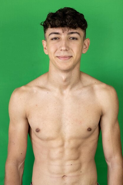 Foto retrato de un joven sin camisa contra un fondo verde